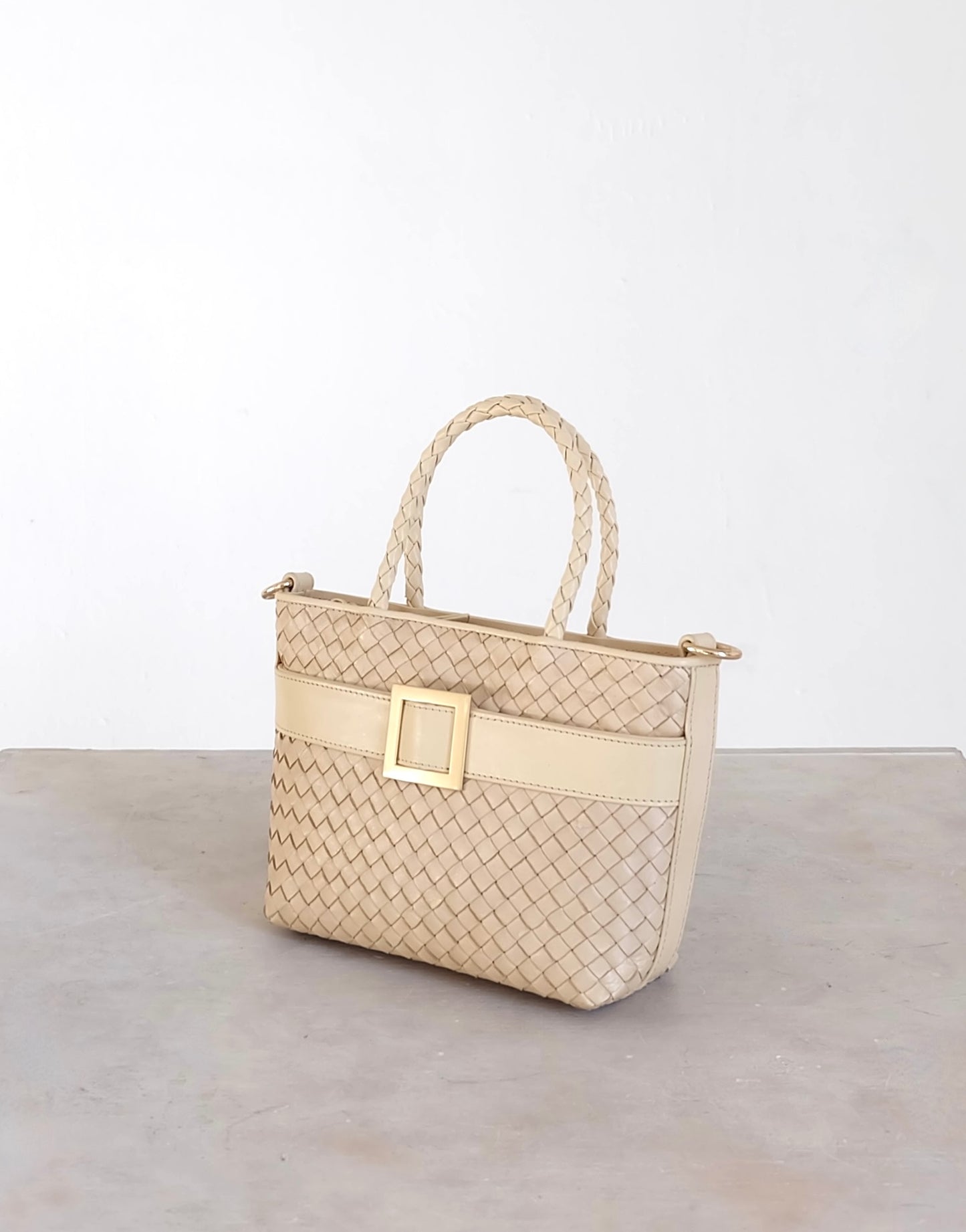Sustainable Italian leather designer handbag in cream. Braided mini tote bag and crossbody in one, with accent buckle and front compartment.