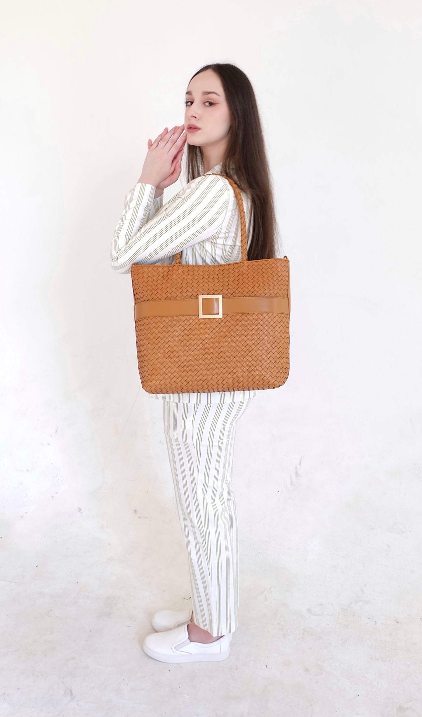 Beautiful, strong, independent, empowered and chic woman wearing a sustainable Italian leather designer handbag, medium tote and crossbody in cognac brown. Handbag with accent buckle that is a functional work of art.