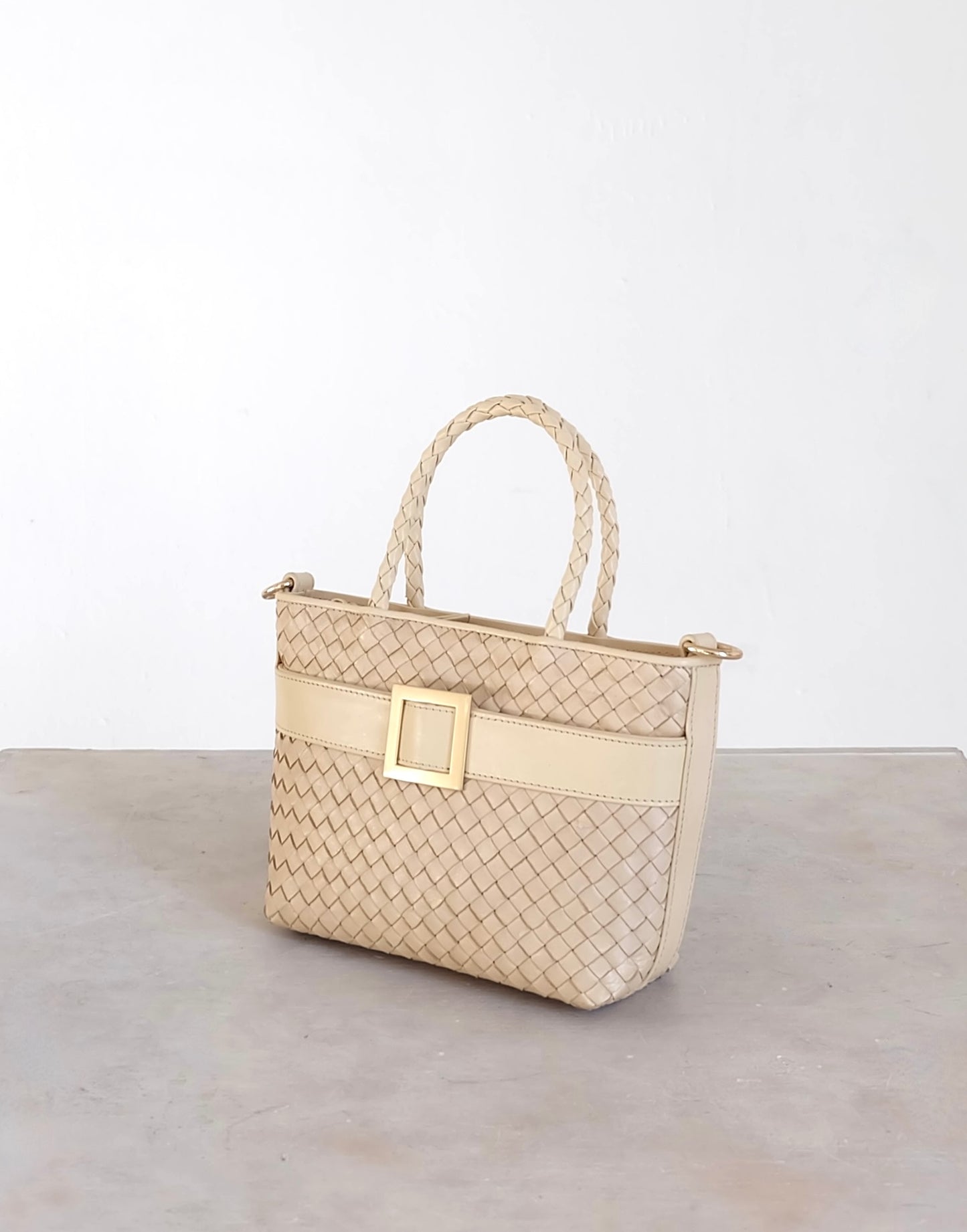 Sustainable Italian leather designer handbag in cream. Braided mini tote bag and crossbody in one, with accent buckle and front compartment.