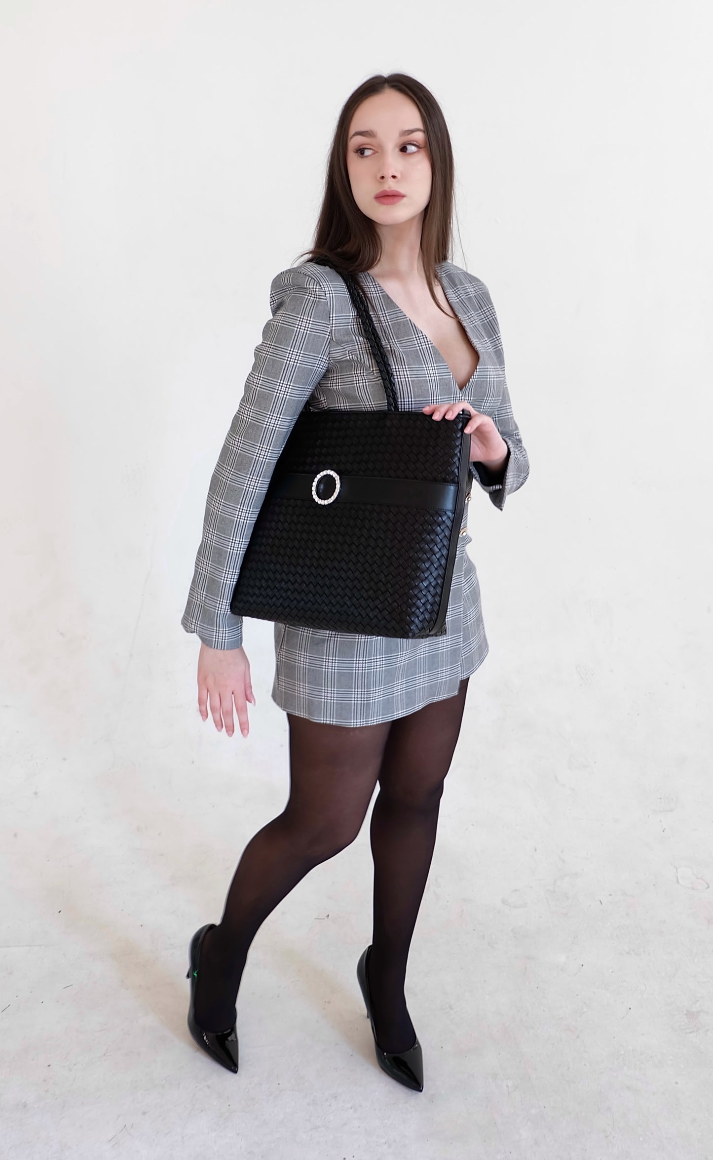 Beautiful, strong, independent, empowered and chic woman wearing a sustainable Italian leather designer handbag, medium tote and crossbody in charcoal-black. Handbag with accent buckle that is a functional work of art.