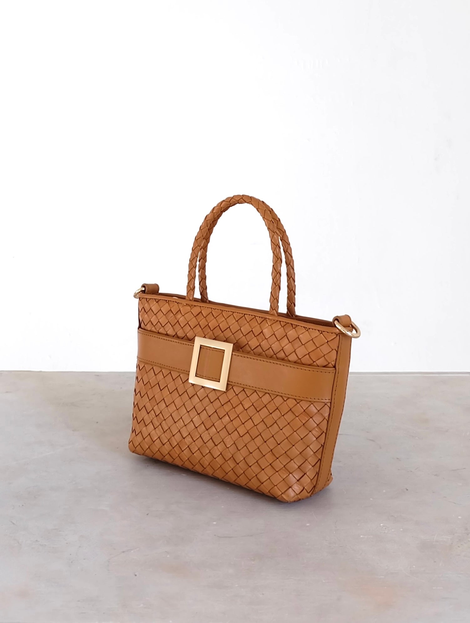 Sustainable Italian leather designer handbag, mini tote and crossbody in cognac brown. Handbag with accent buckle that is a functional work of art.