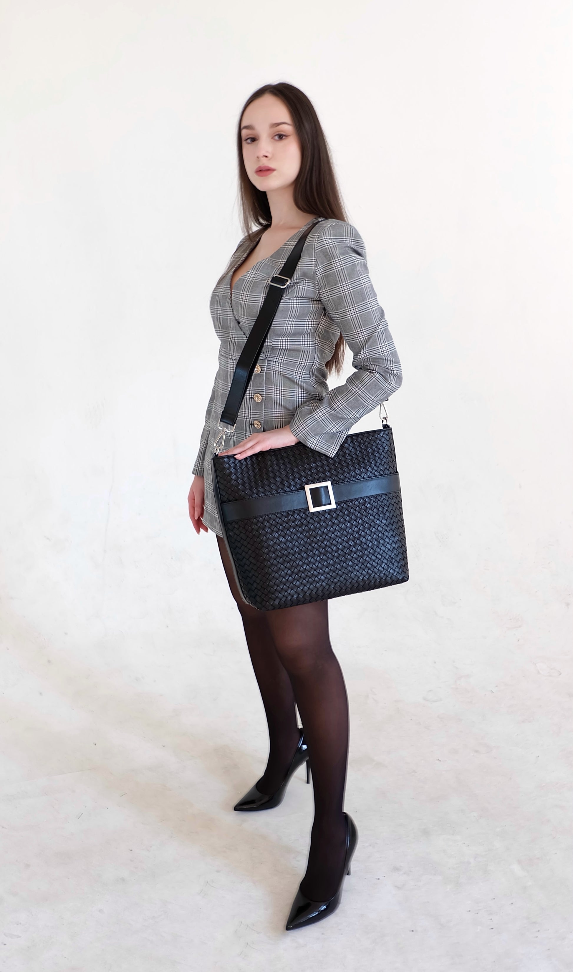 Beautiful, strong, independent, empowered and chic woman wearing a sustainable Italian leather designer handbag, medium tote and crossbody in charcoal-black. Handbag with accent buckle that is a functional work of art.