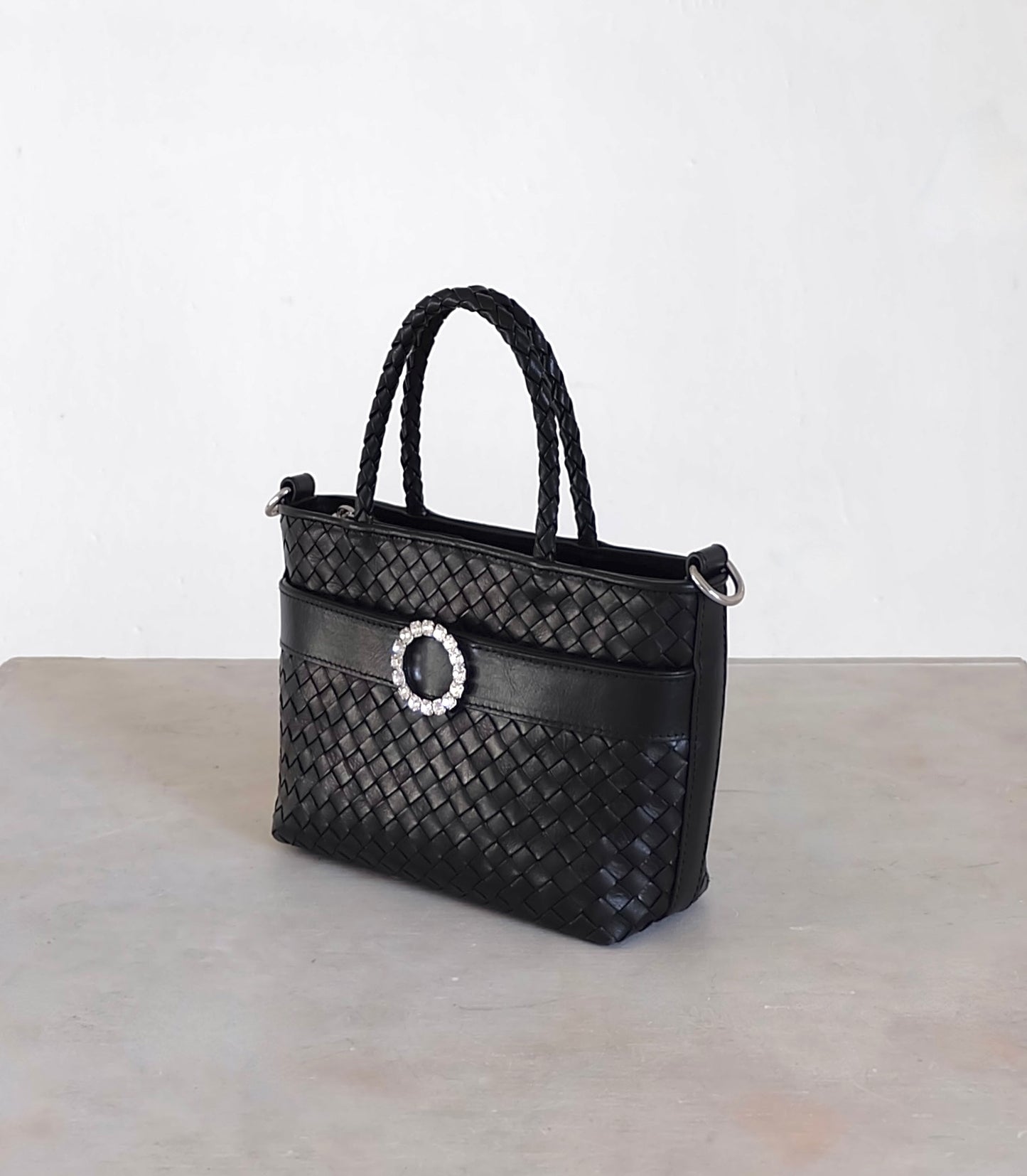 Sustainable Italian leather designer handbag in charcoal black. Braided mini tote bag and crossbody in one, with accent buckle and front compartment.